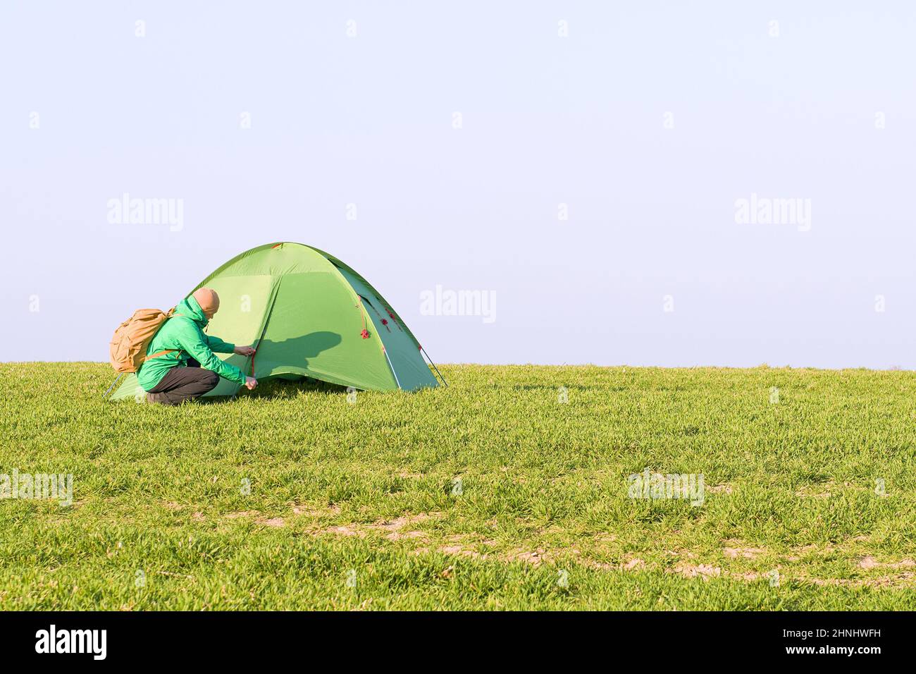 Tourist with hands up near his tent on summer field Stock Photo