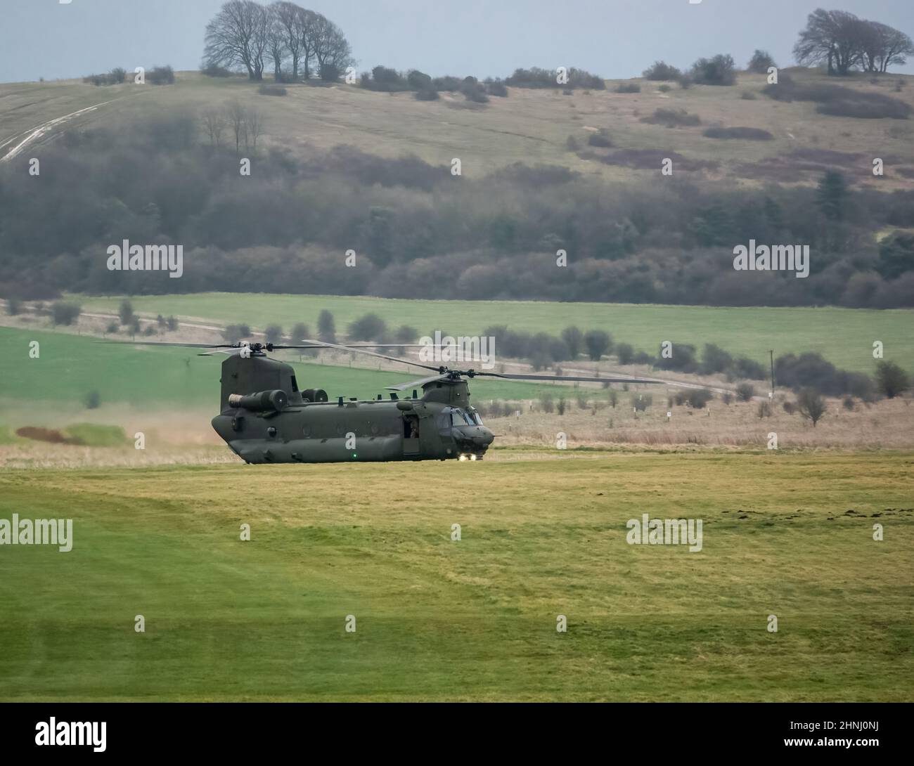 RAF Chinook tandem-rotor CH-47 helicopter preparing for takeoff in a cloudy blue grey sky on a military battle exercise, Wilts UK Stock Photo