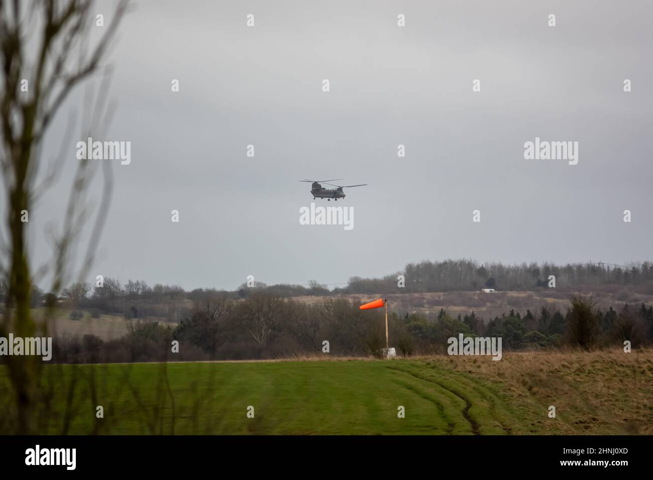 RAF Chinook tandem-rotor CH-47 helicopter flying fast and low in a cloudy blue grey sky on a military battle exercise, Wilts UK Stock Photo