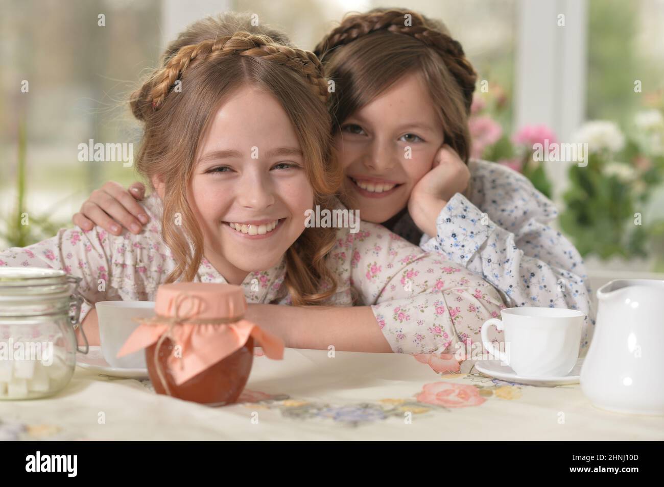 Two smiling little girls drinking tea at home Stock Photo