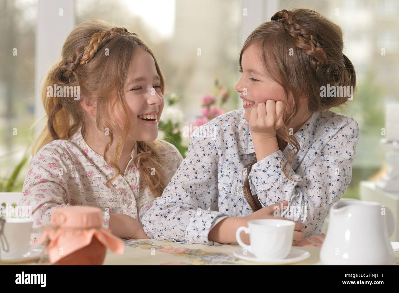 Two smiling little girls drinking tea at home Stock Photo