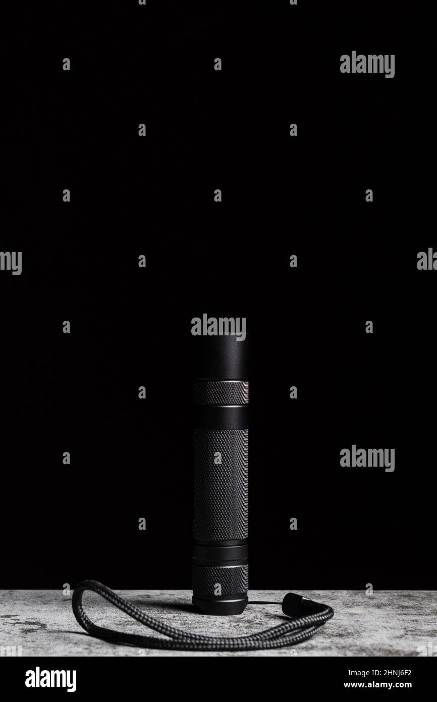 Flashlight stands on a table on a black background with vertical copy space. Stock Photo