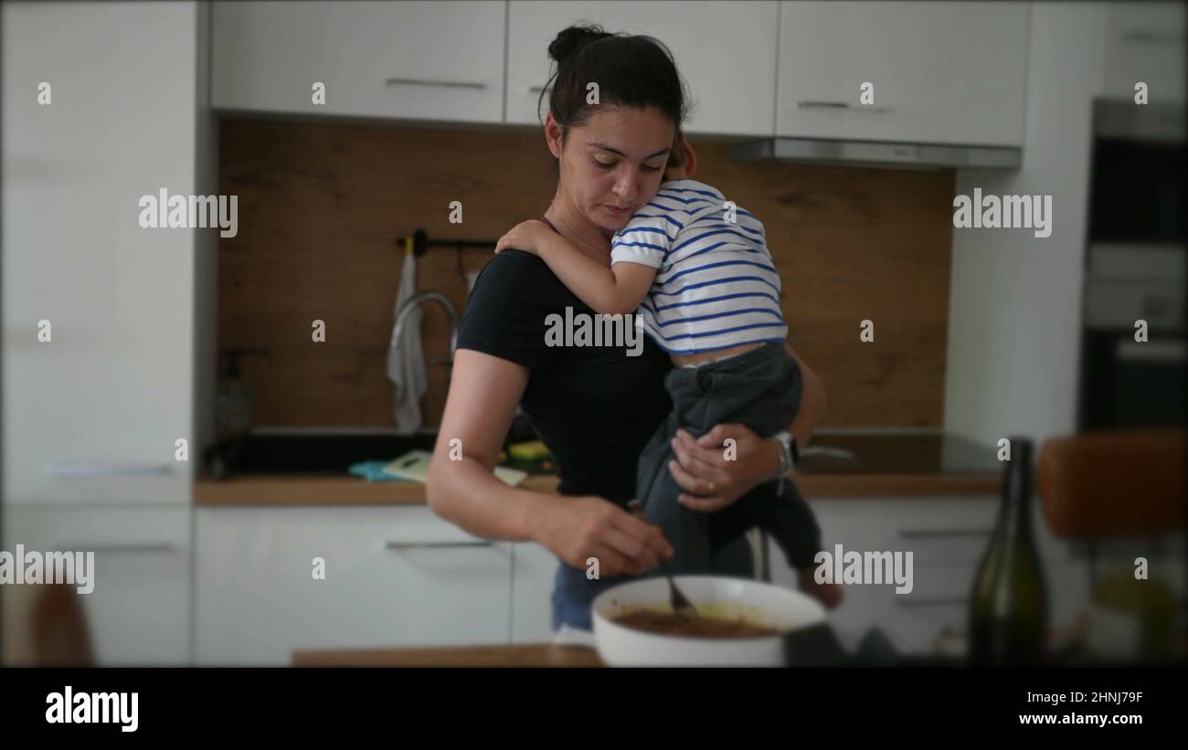 Mother cooking while holding baby toddler child Stock Photo - Alamy
