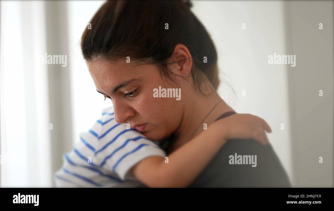 Mother multi-tasking at home holding child in arms Stock Photo - Alamy