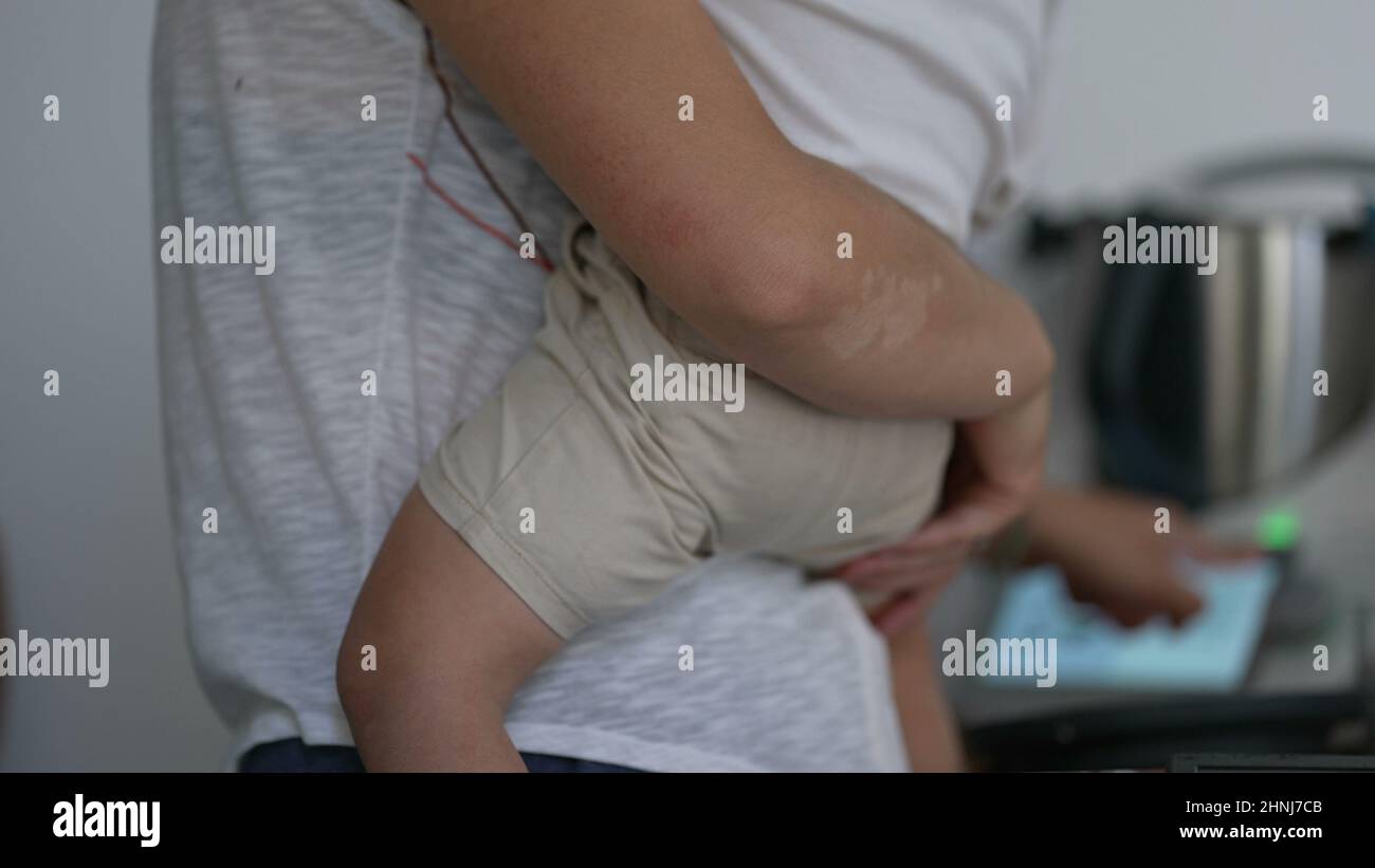 Mother multi-tasking at home holding child in arms Stock Photo - Alamy