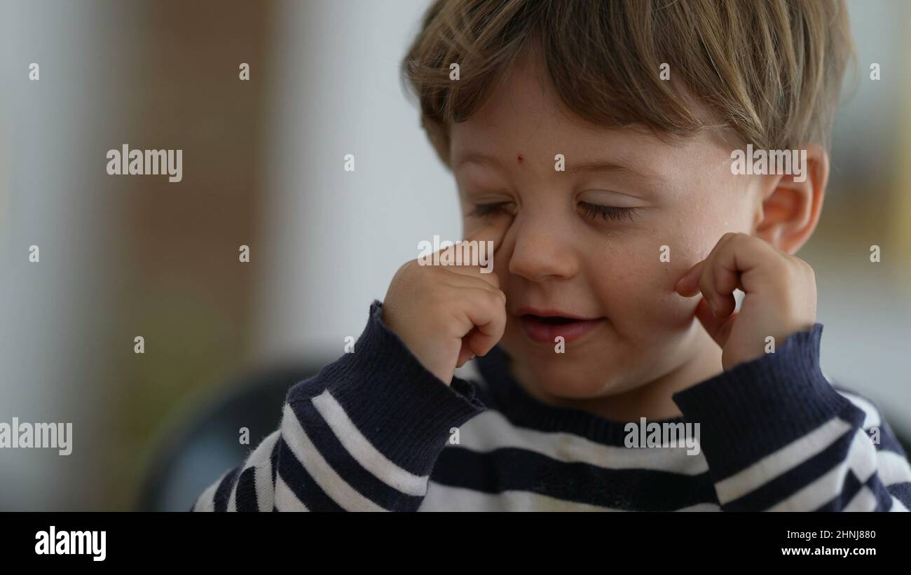 Toddler touching eyes and face with hand child rubbing face with finger
