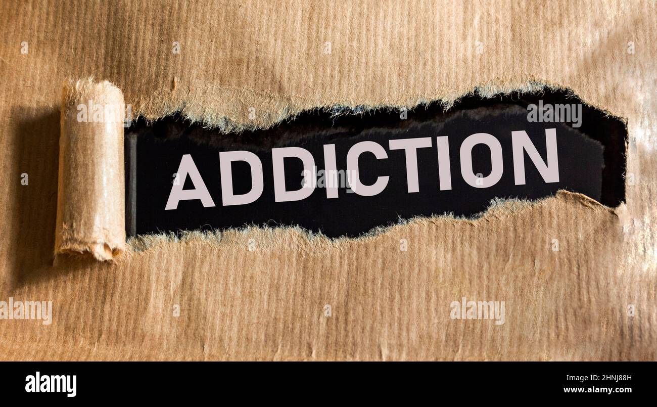 The word Addiction is written under brown torn paper. Stock Photo