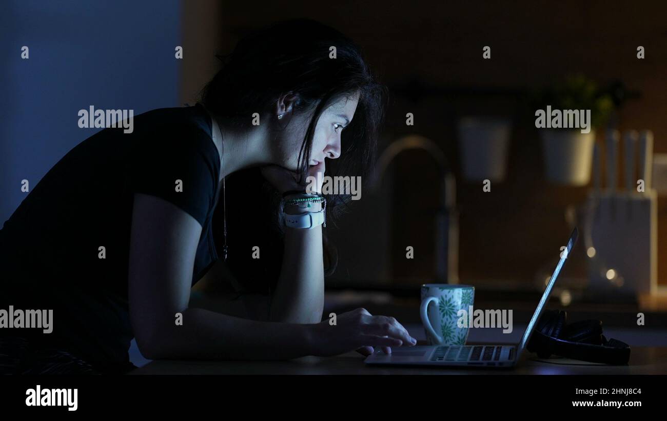 Woman browsing internet in front of laptop screen at night Stock Photo ...