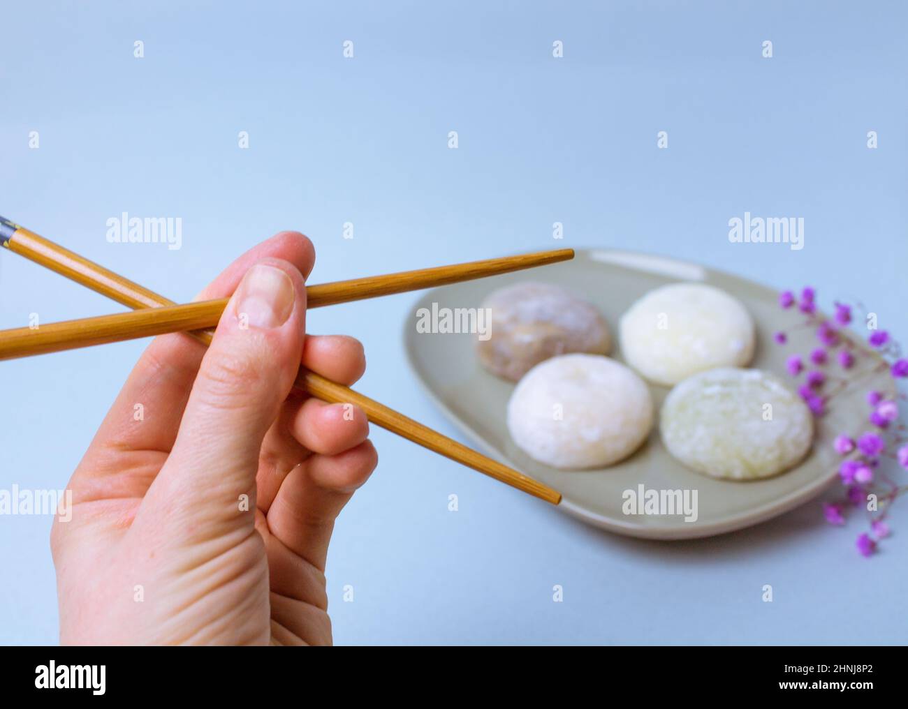 Chopsticks in a hand. Going to eat traditional Japanese dessert mochi rice dough Stock Photo