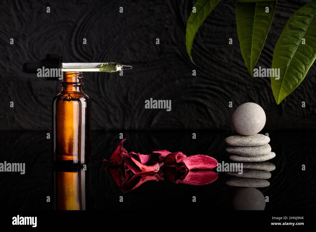 Cosmetological product for facial care. Serum in glass amber bottle with pipette on black background. Essential oil for care of women's skin. Spa comp Stock Photo