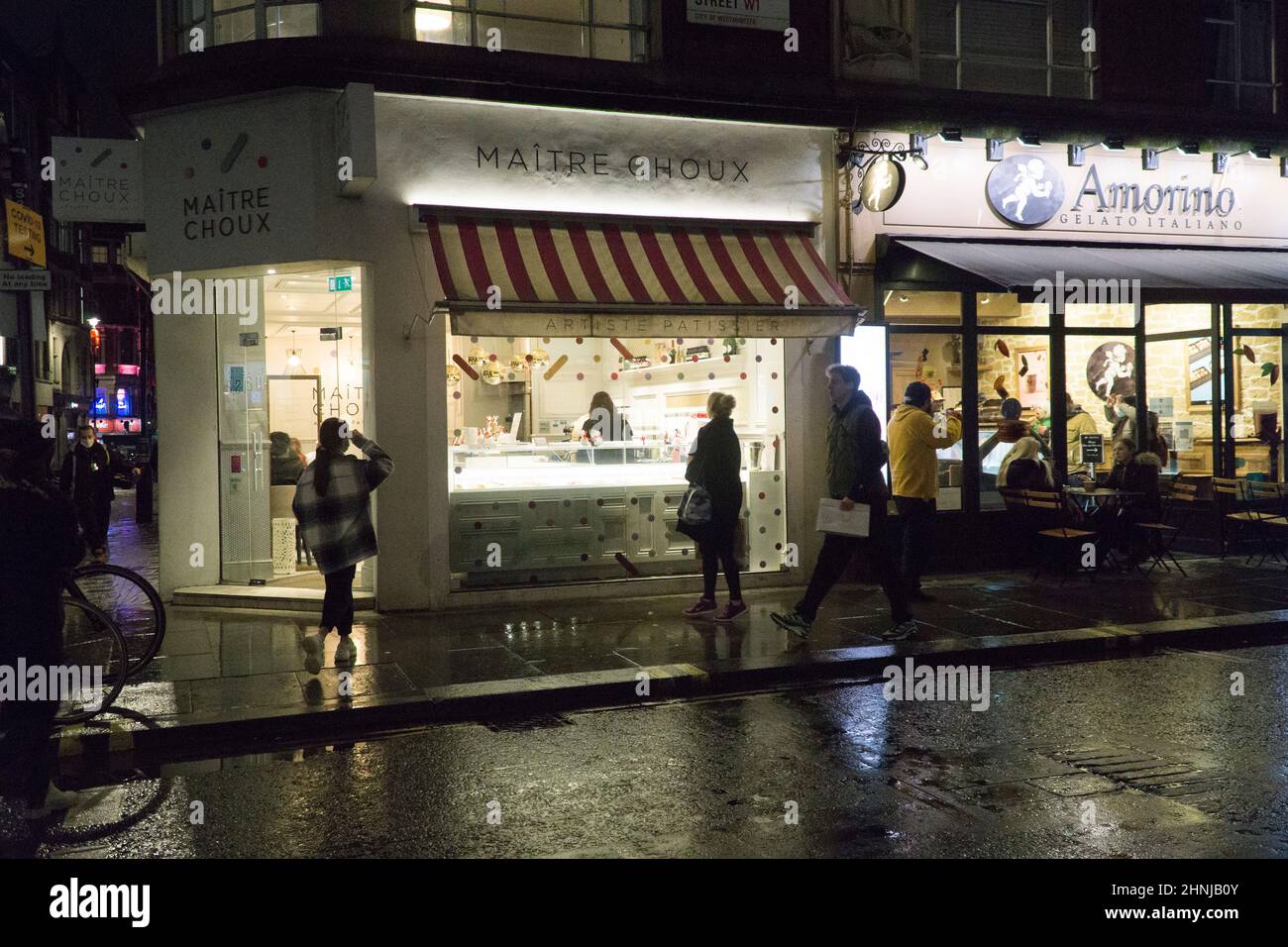 London, UK, 16 February 2022: In Soho at night the lights are reflecting off the street on a rainy evening. The area used to be known for it's sleeze Stock Photo