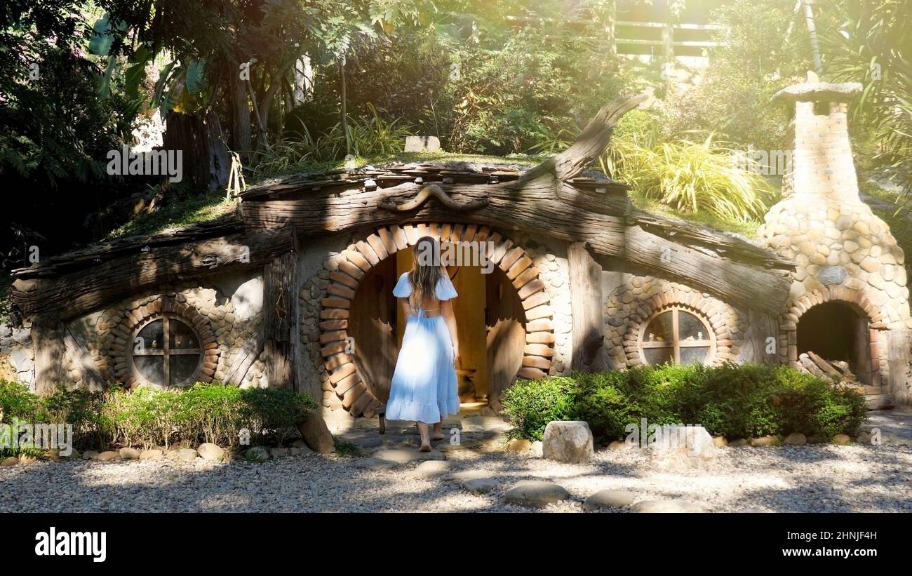 Back view of young beautiful woman going in small hobbits house Stock Photo