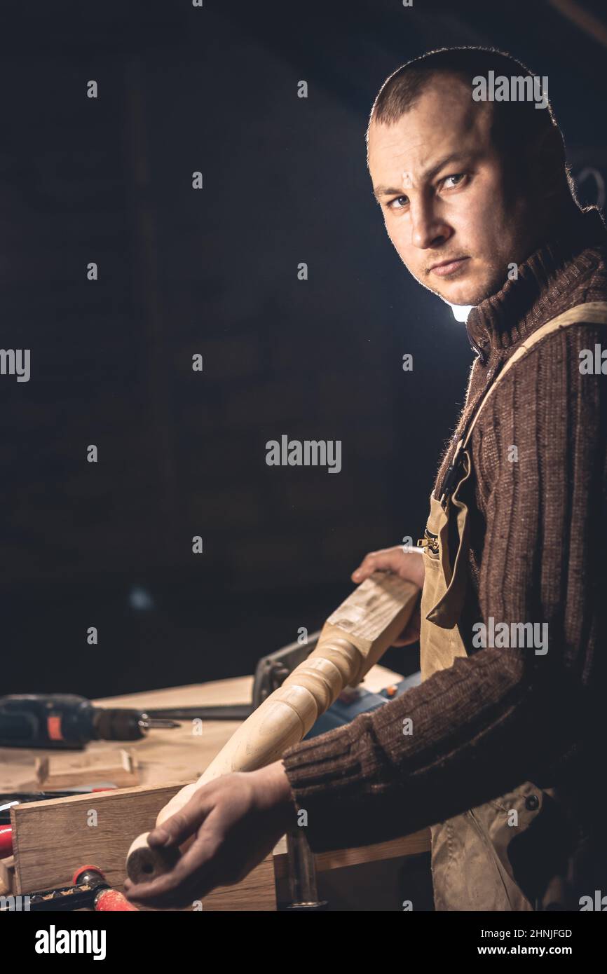A man makes wood products with the help of special tools. Portrait of a young carpenter at work. Employment in the woodworking industry Stock Photo