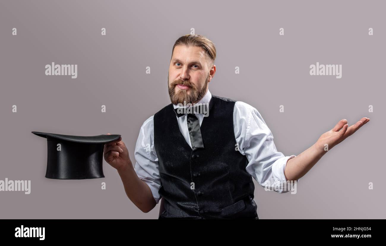 Retro magician holding top hat Stock Photo - Alamy