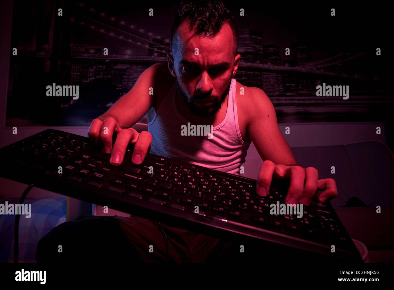 a gamer of thirty years old with a keyboard in his hands plays computer ...