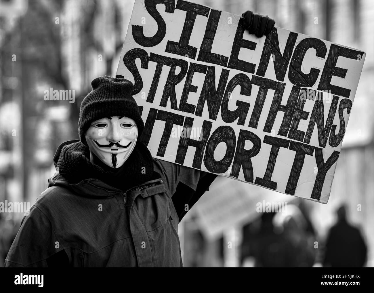 Protester wearing anonymous face mask marches in support of free speech at the Queens Park Covid-19 vaccination mandate protest in Toronto, Canada. Stock Photo