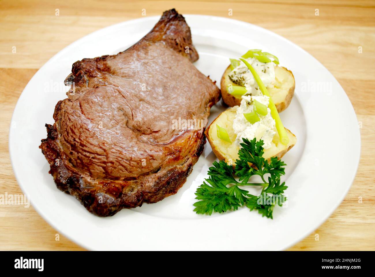 A Broiled Prime Rib Steak Served with Baked Potato and Scallions Stock ...