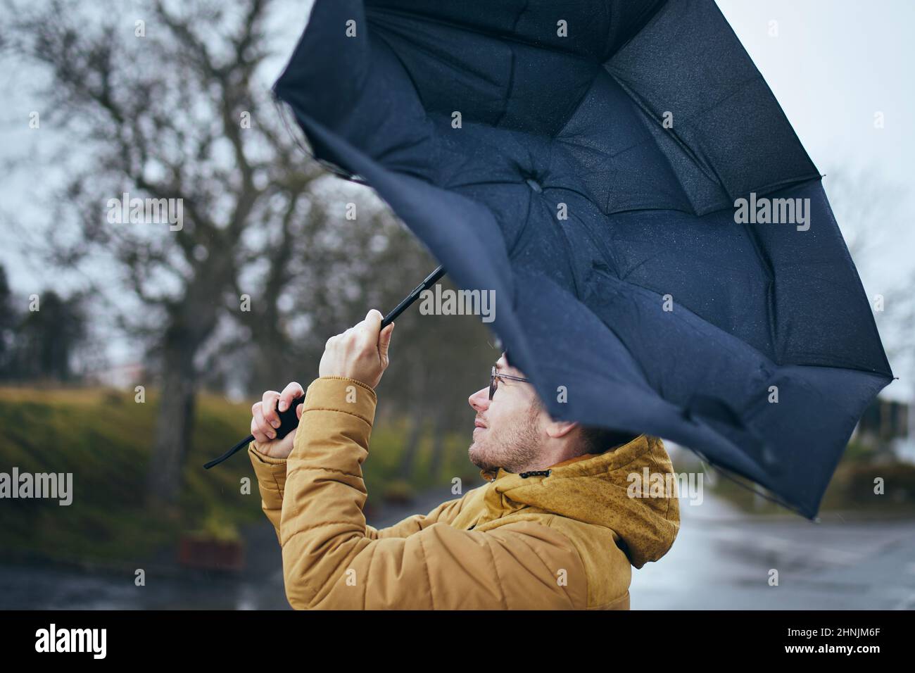 Man holding broken umbrella in strong wind during gloomy rainy day. Themes weather and meteorogy. Stock Photo