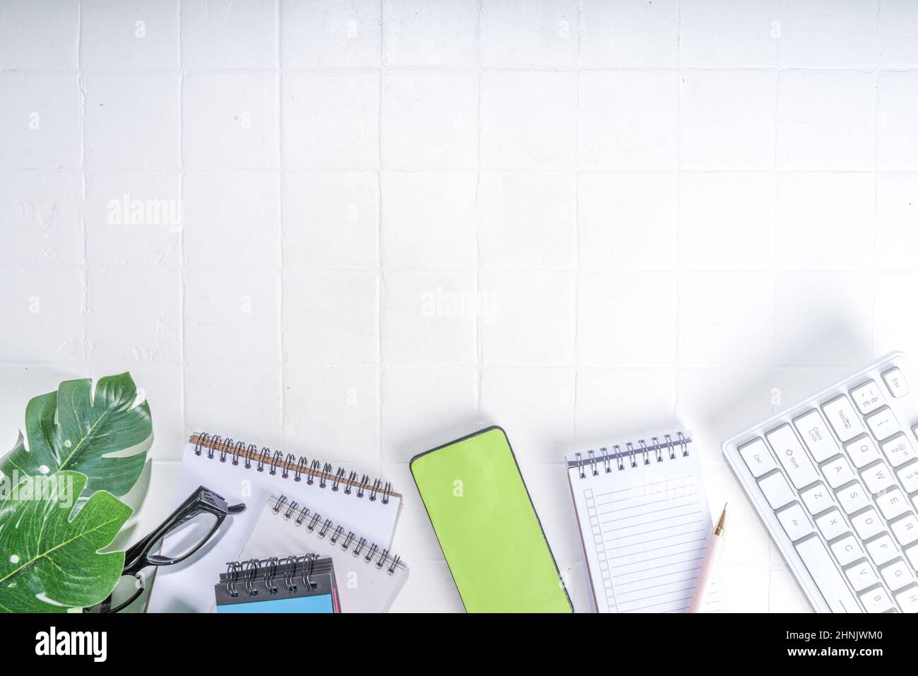 Office desk background. Laptop keyboard, smartphone and various work supplies on office white ...