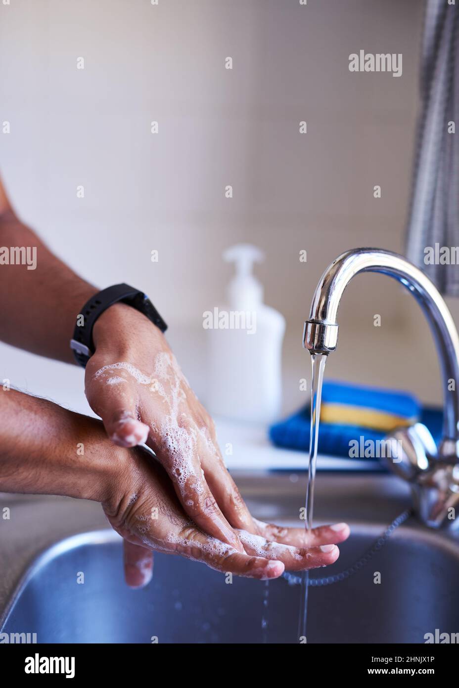 Close up shot of an adult man washing his hands in the kitchen sink