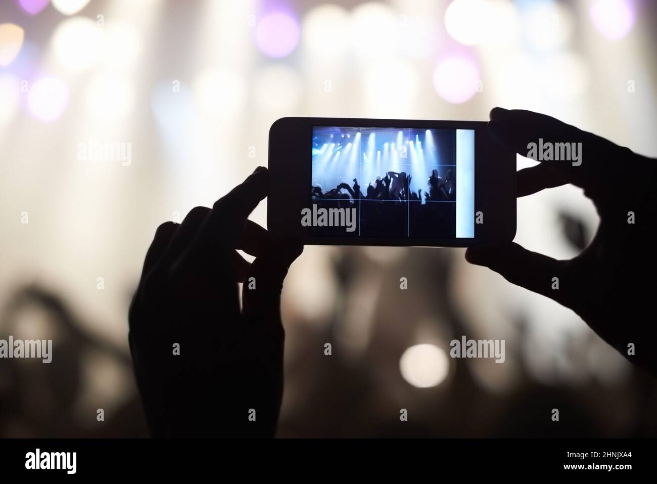 A person filming their favourite band with a camera phone. This concert was created for the sole purpose of this photo shoot, featuring 300 models and Stock Photo