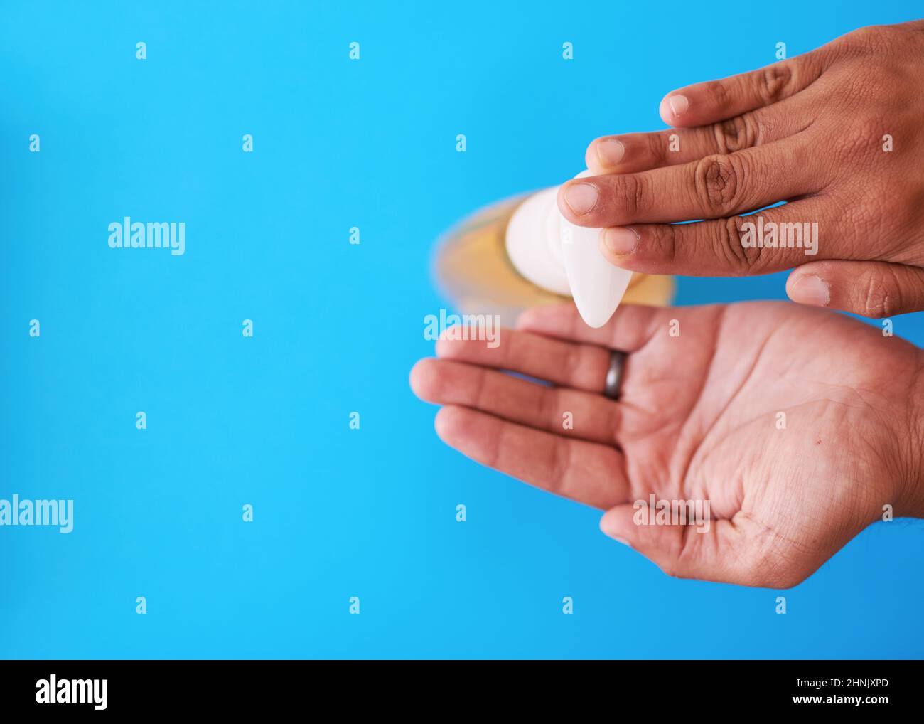 An overhead shot of a man dispensing soap against a blue background Stock Photo