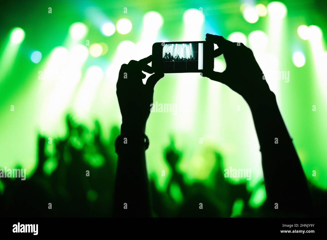 A person filming their favorite band with a camera phone. This concert was created for the sole purpose of this photo shoot, featuring 300 models and Stock Photo