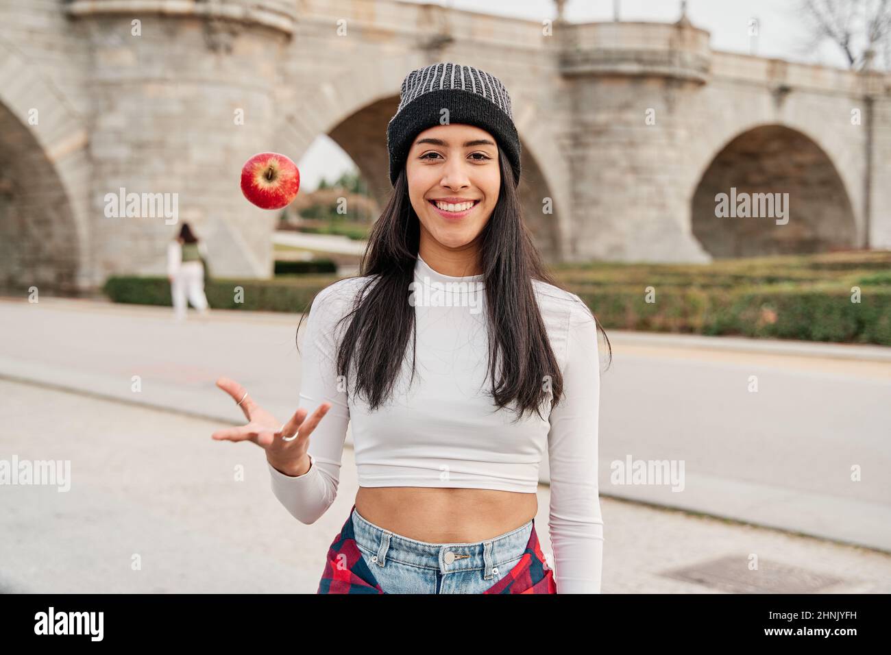young latin woman smiling and throwing an apple Stock Photo
