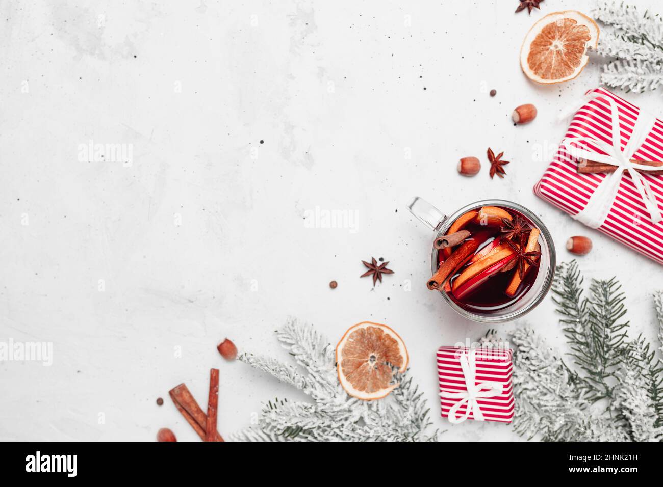 Christmas flat lay top view on white gray concrete background table with glass cup or mug of Mulled Wine, present red gift boxes, decorations, cinnamo Stock Photo