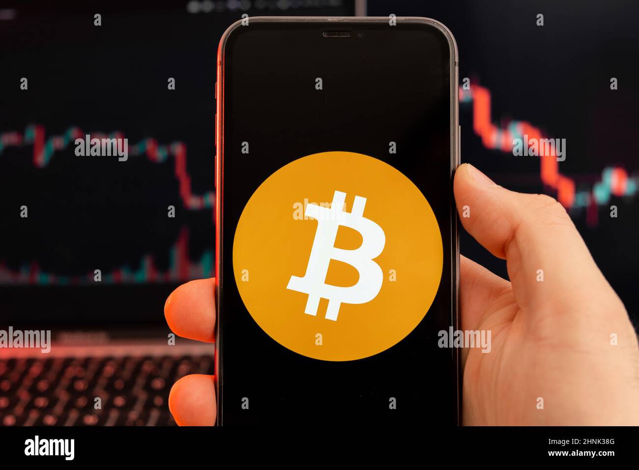Bitcoin BTC app of cryptocurrency stock market analysis on the screen of mobile phone in man hands and downtrend charts trading data on the background, February 2022, San Francisco, USA. Stock Photo