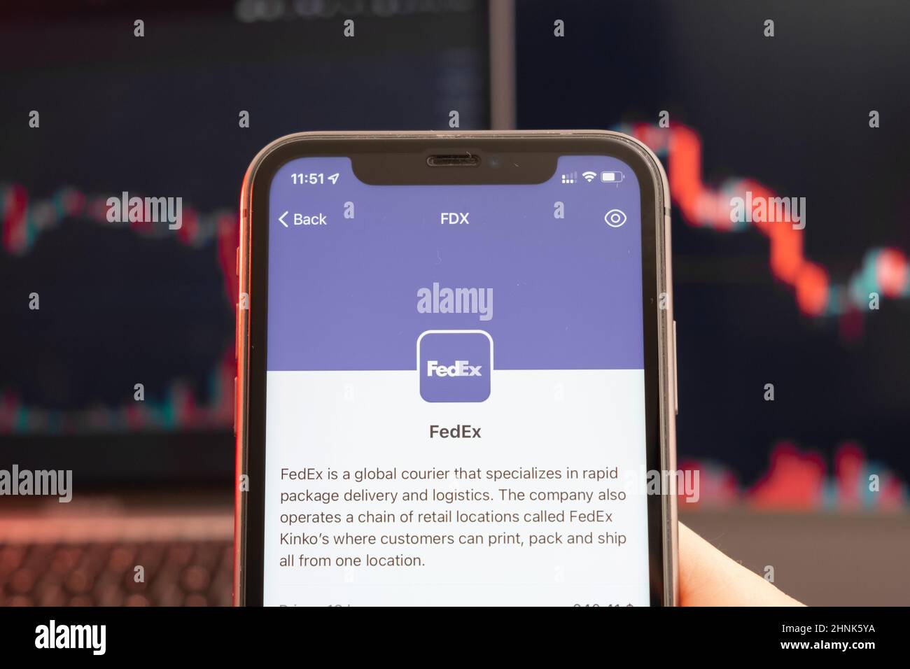 FedEx stock price decrease on the trading market with downtrend line graph bar chart on the background. Man holding a mobile phone with company logo, February 2022, San Francisco, USA.  Stock Photo