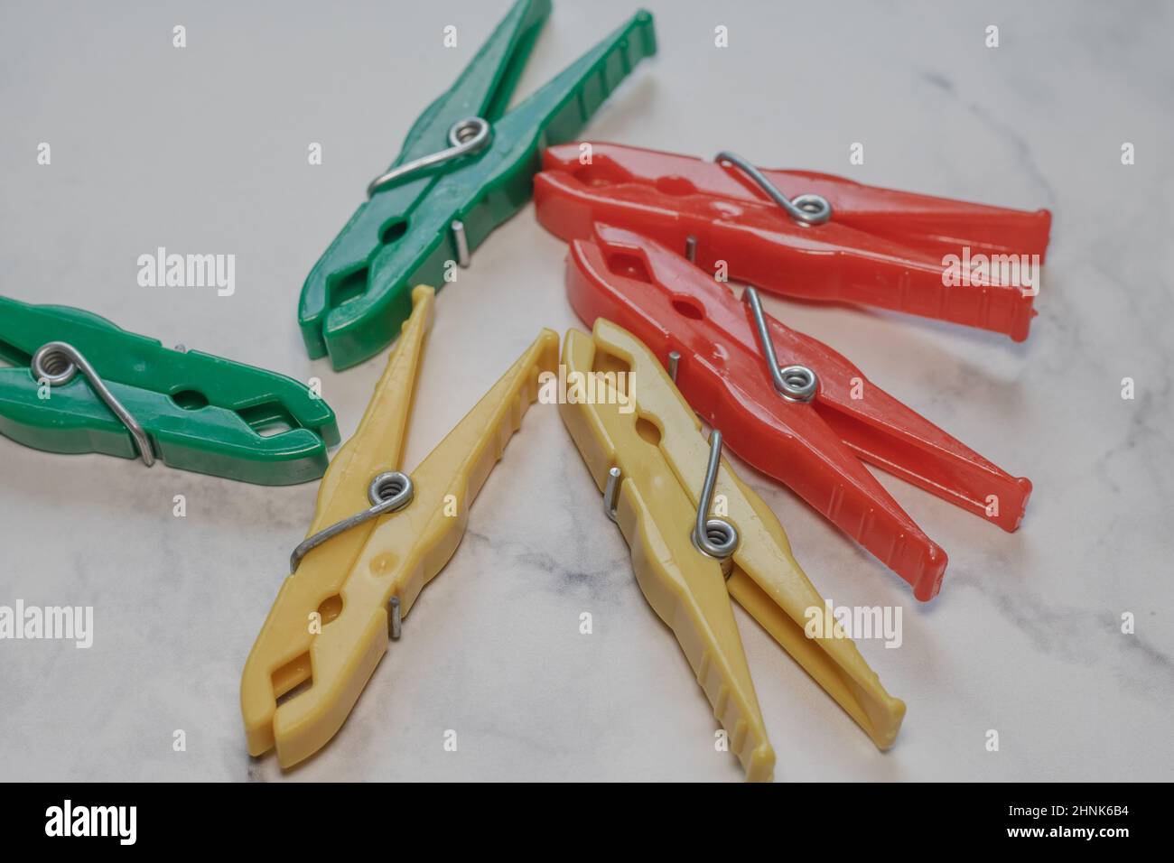 Different classic clothespins made of plastic from a surface with marble structure Stock Photo