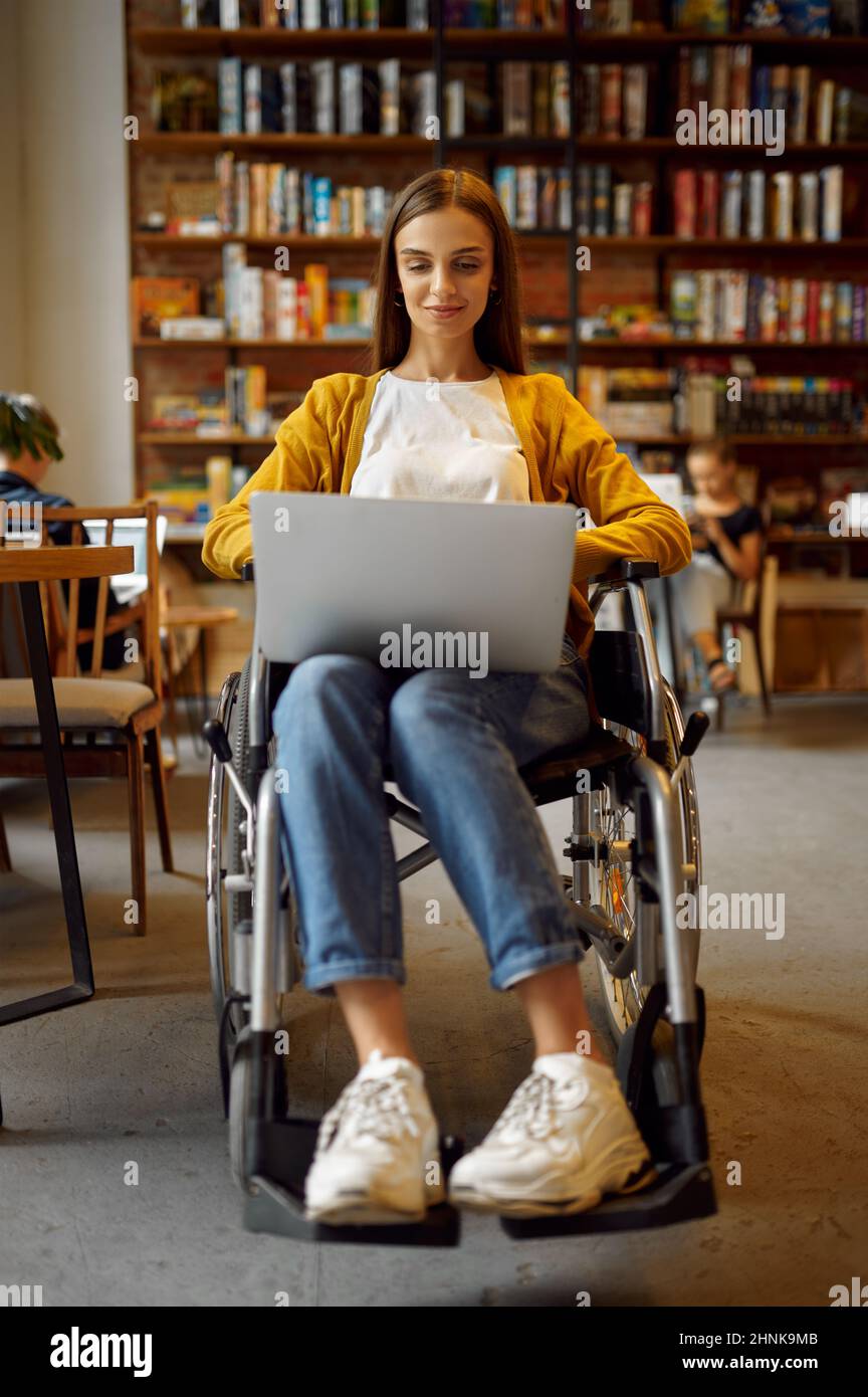 Disabled female student in wheelchair works on laptop, disability ...