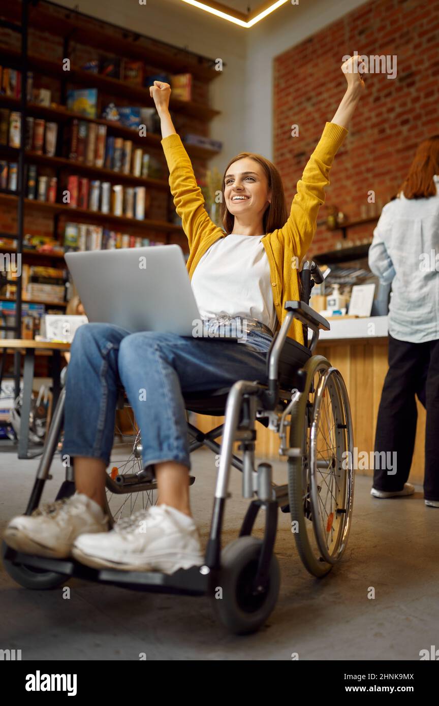 Cheerful female student in wheelchair, disability, bookshelf and
