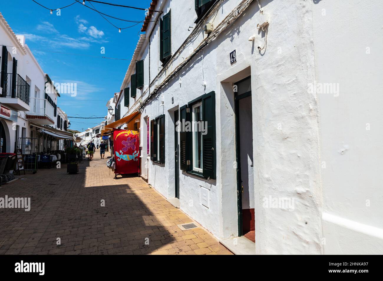 Fornells, Spain - July 21, 2021: Street of the fishing village of Fornells with people around on summer in Menorca, Balearic island, Spain Stock Photo