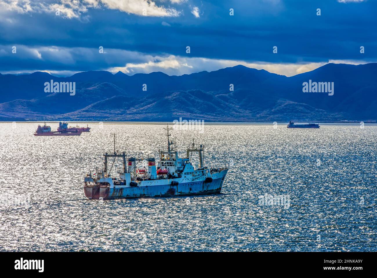 large fishing vessel on the background of hills and volcanoes. Selective focus Stock Photo
