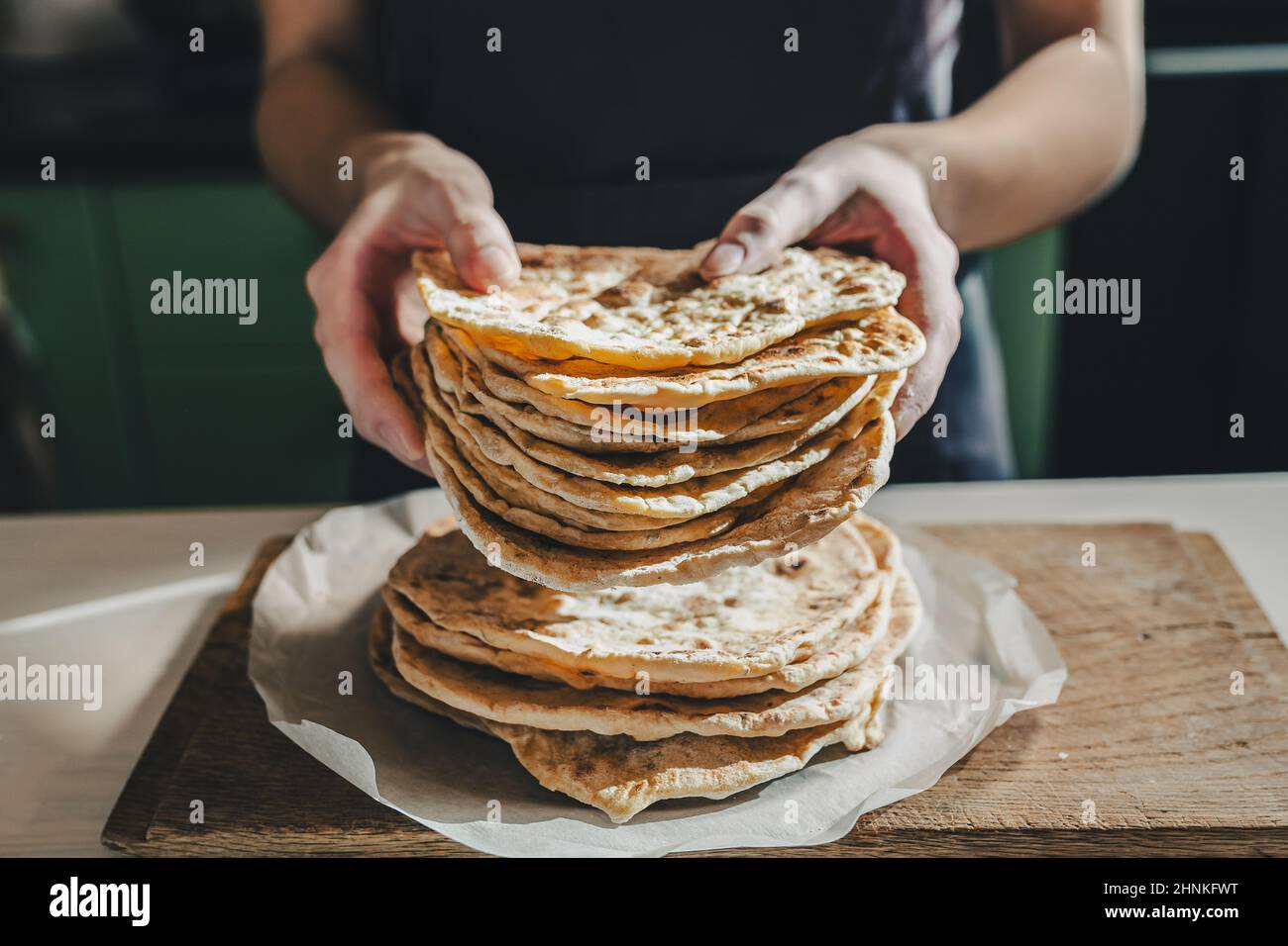 Thin round cakes of lavash are stacked, hands of cook stretch lavash forward for testing. Spanish flatbread or armenian lavash close-up Stock Photo