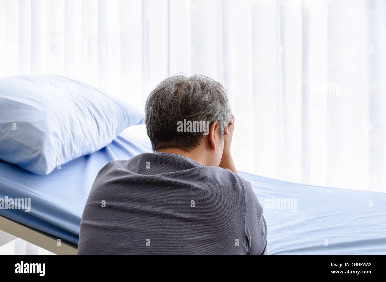 Relative of patient grieving on bed in the hospital ward. Stock Photo