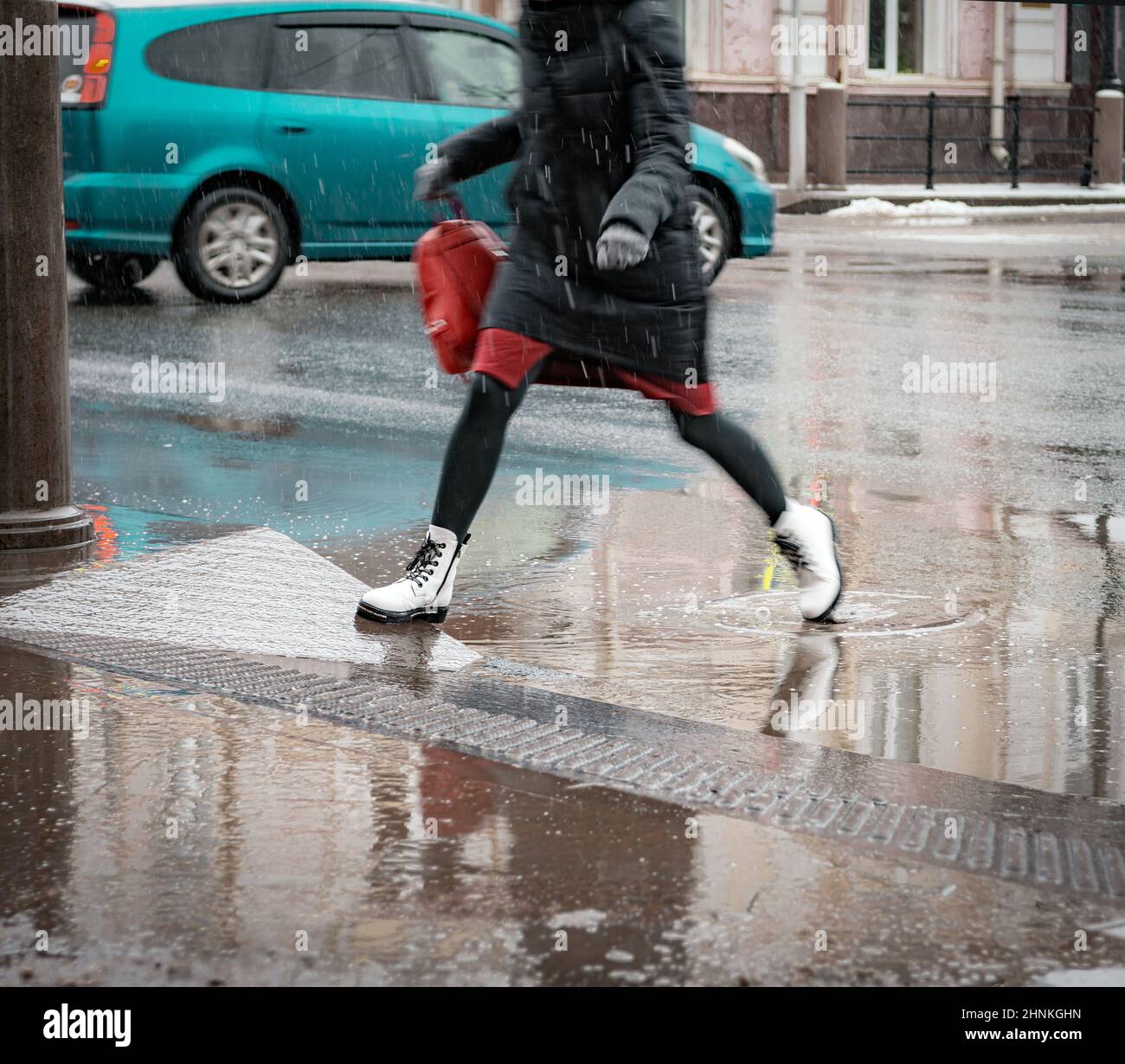 lady jumps over puddle on the street Stock Photo