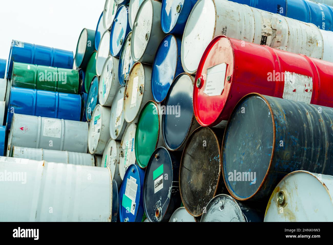 Old chemical barrels with flammable liquid warning label . Steel oil tank. Toxic waste in metal tank. Hazardous chemical barrel. Hazard waste storage in factory. Chemical barrels stack. Oil brent. Stock Photo