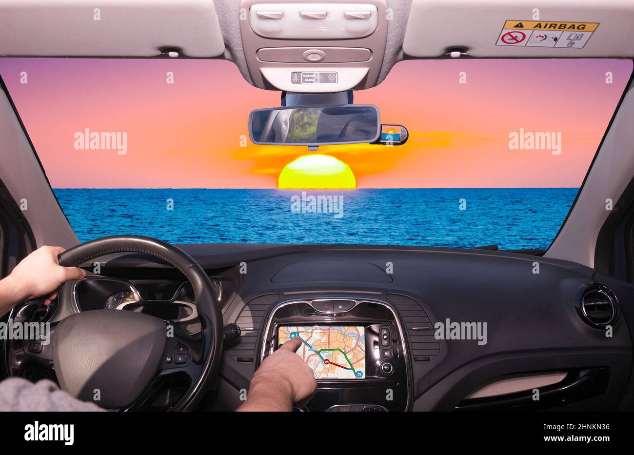 Driving using GPS towards a beautiful sunset by the sea, Italy Stock Photo
