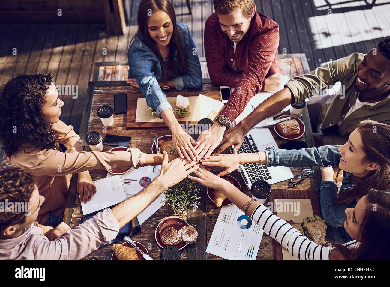 Because teams who eat together, stay together. High angle shot of a group of creative workers piling their hands while out on a business lunch. Stock Photo