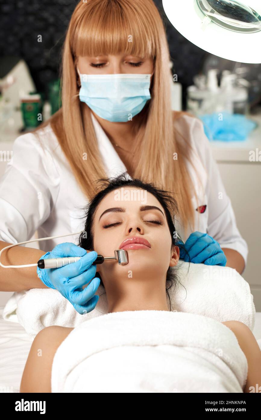 Beautician makes cleaning of face in spa salon. Stock Photo