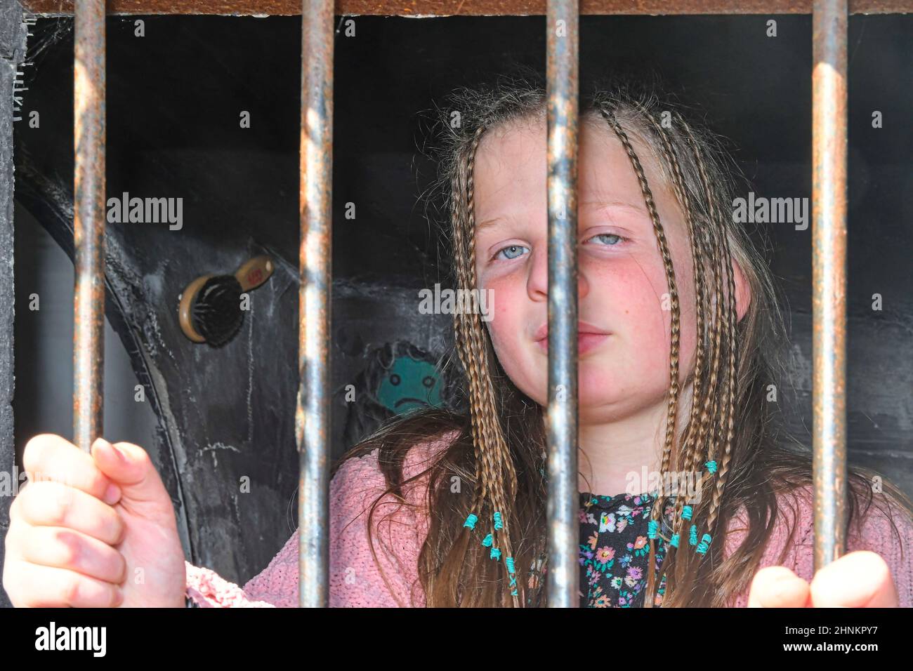 Sad little girl behind iron bars. Little girl behind the bars. Violence concept Stock Photo