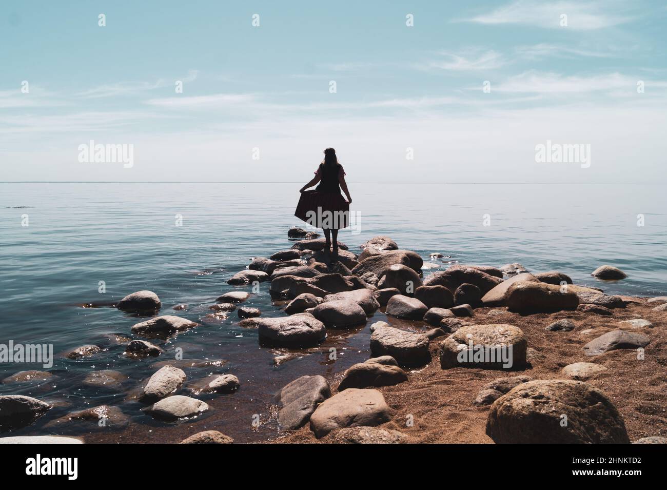 Silhouette of a woman standing on stones at the beach. beautiful summer ...