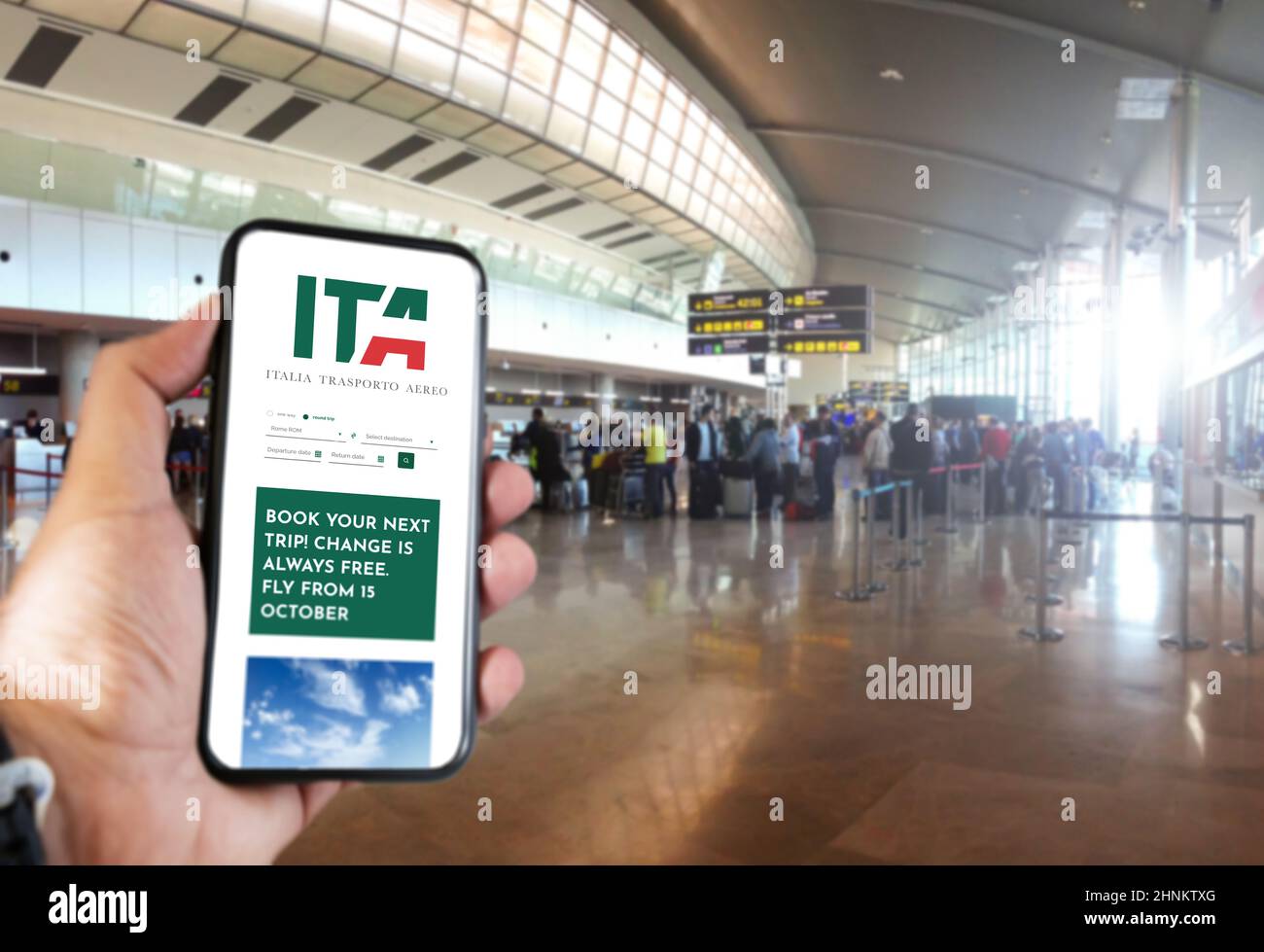 Hand holding a smart phone with the ITA app on the screen in the airport Stock Photo