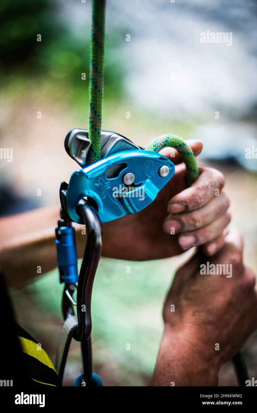 Man's hands operating a rock climbing belaying device Stock Photo