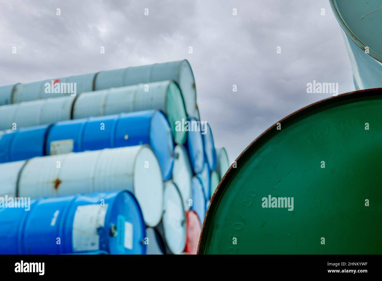 Selective focus on green old chemical barrels stack. Steel tank of flammable liquid. Hazard chemical barrel. Industrial waste. Empty chemical barrels at the factory warehouse. Hazard waste. Stock Photo