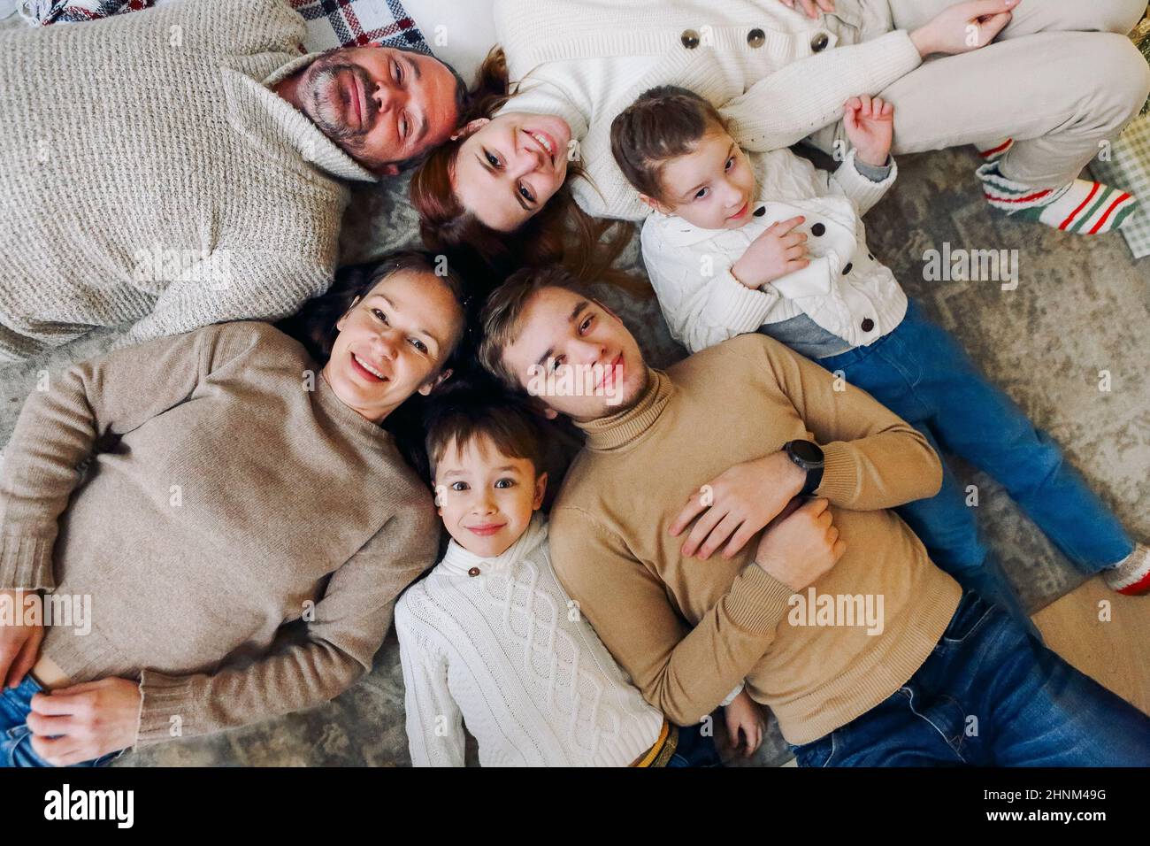 Top view of happy big multi-generation family lying in circle on floor and smiling at camera, strengthening bonds and building healthy relationships r Stock Photo