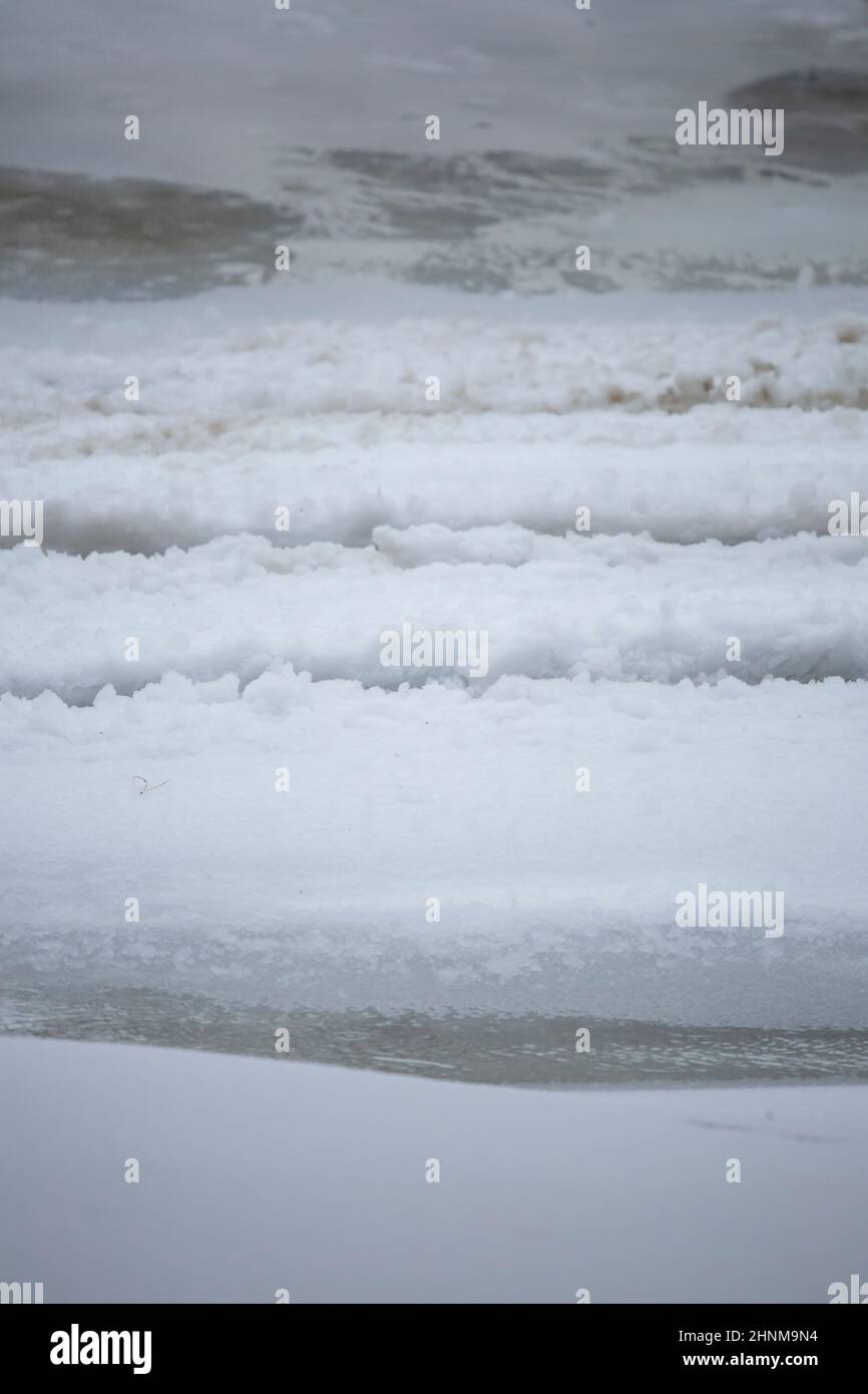 Partially frozen water flowing in ruts in the snow and ice Stock Photo